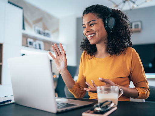woman waving as she remotes into her work for the day