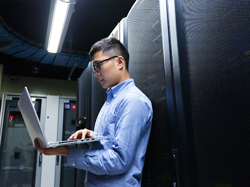 man working on a laptop standing in the server room