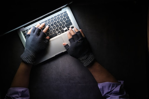 person typing on a laptop with fingerless gloves on